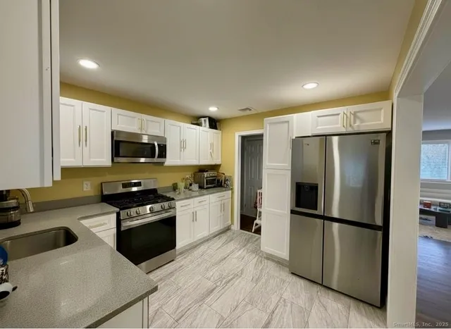 a kitchen with stainless steel appliances granite countertop a refrigerator a stove microwave and sink