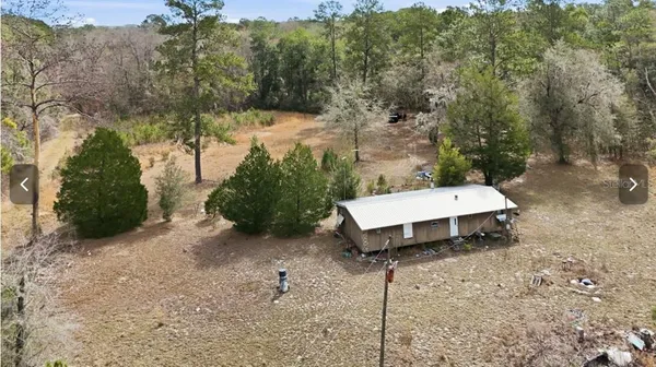 a view of a wooden house with a yard and hanging chair