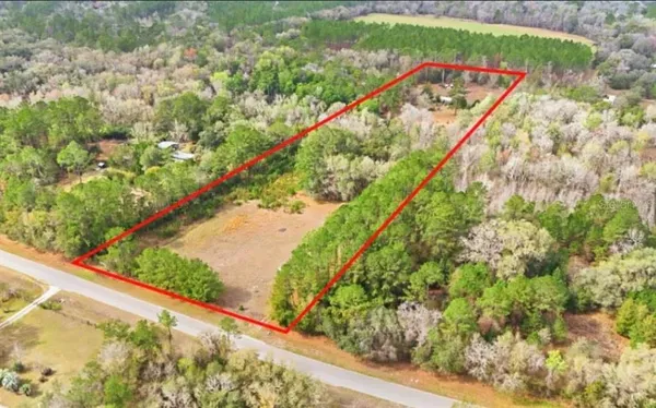 an aerial view of residential houses with outdoor space and trees