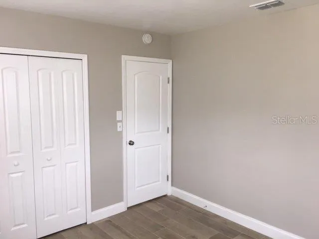 an empty room with wooden floor and closet area