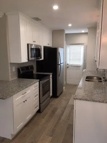 a kitchen with granite countertop a refrigerator and a sink