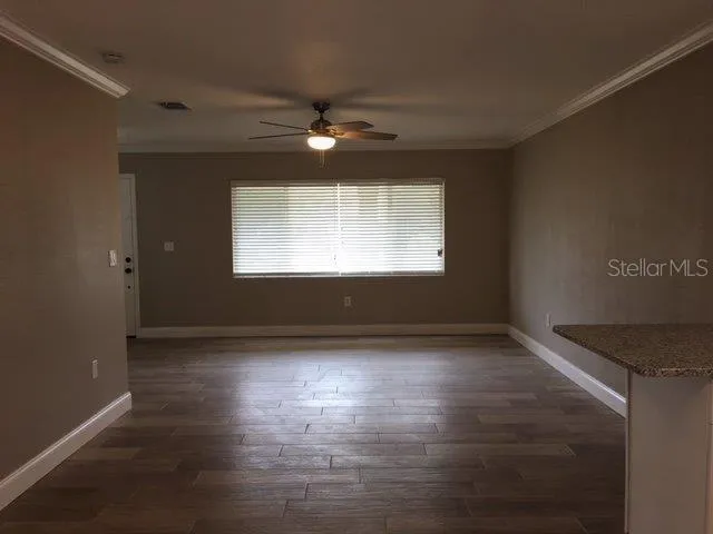 a view of an empty room with wooden floor and a window
