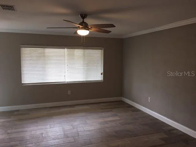 a view of an empty room with wooden floor and a window