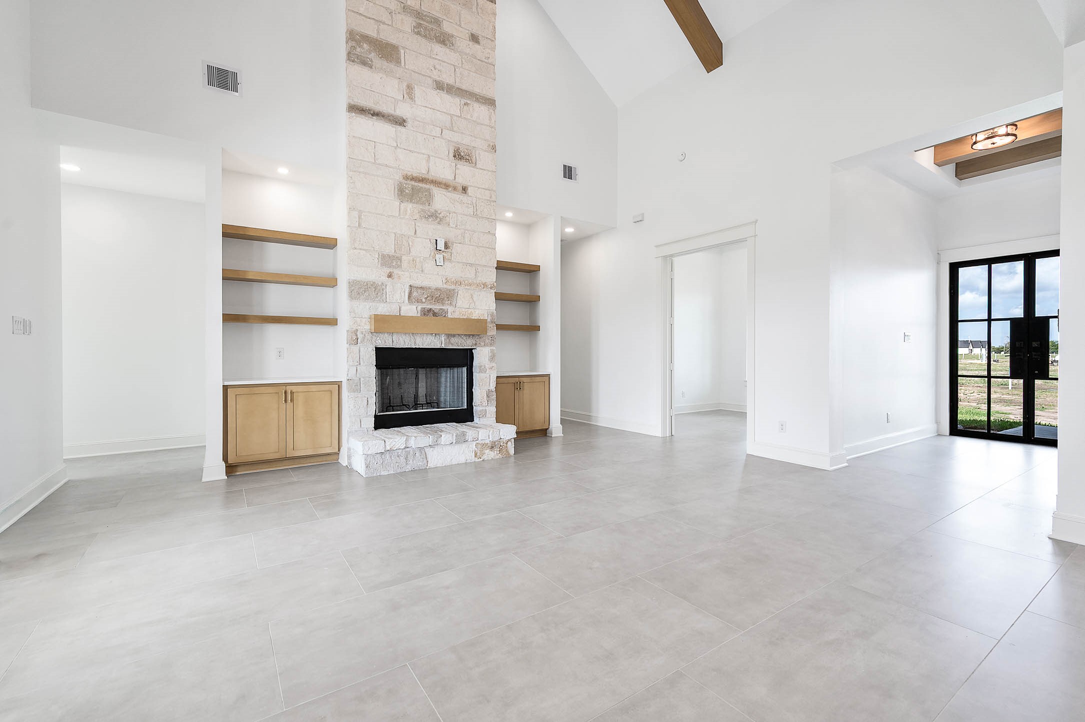 13927 Routt Point Road Needville, TX 77461 - Photo 8 of 21 Spacious living area with high ceilings, a stone fireplace, built-in shelving, and plenty of natural light.