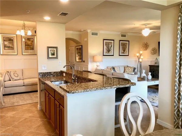 a living room with stainless steel appliances granite countertop a sink and a stove