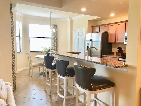 a kitchen with a dining table chairs sink and granite counter top