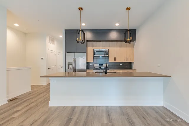 a large kitchen with stainless steel appliances a large counter top a stove and a wooden floors