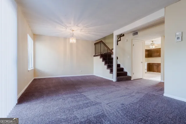 a view of an empty room with stairs and a ceiling fan