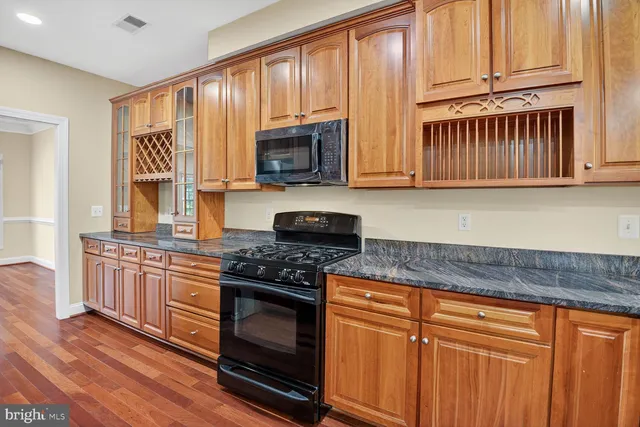 a kitchen with granite countertop cabinets stainless steel appliances and a wooden floor