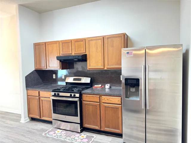 a kitchen with stainless steel appliances granite countertop a stove a refrigerator and a microwave