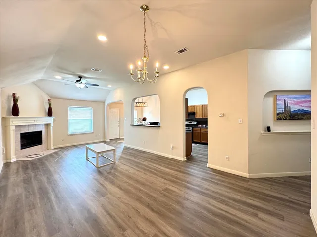 a view of a livingroom with wooden floor and a kitchen