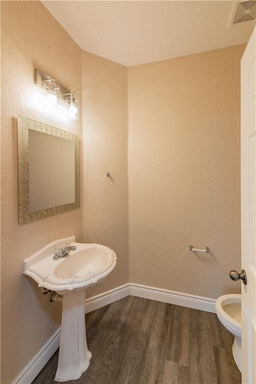 12017 Springs Head Loop Austin, TX 78717 - Photo 9 of 25 A compact and functional bathroom features a classic pedestal sink and elegant wood-look flooring.