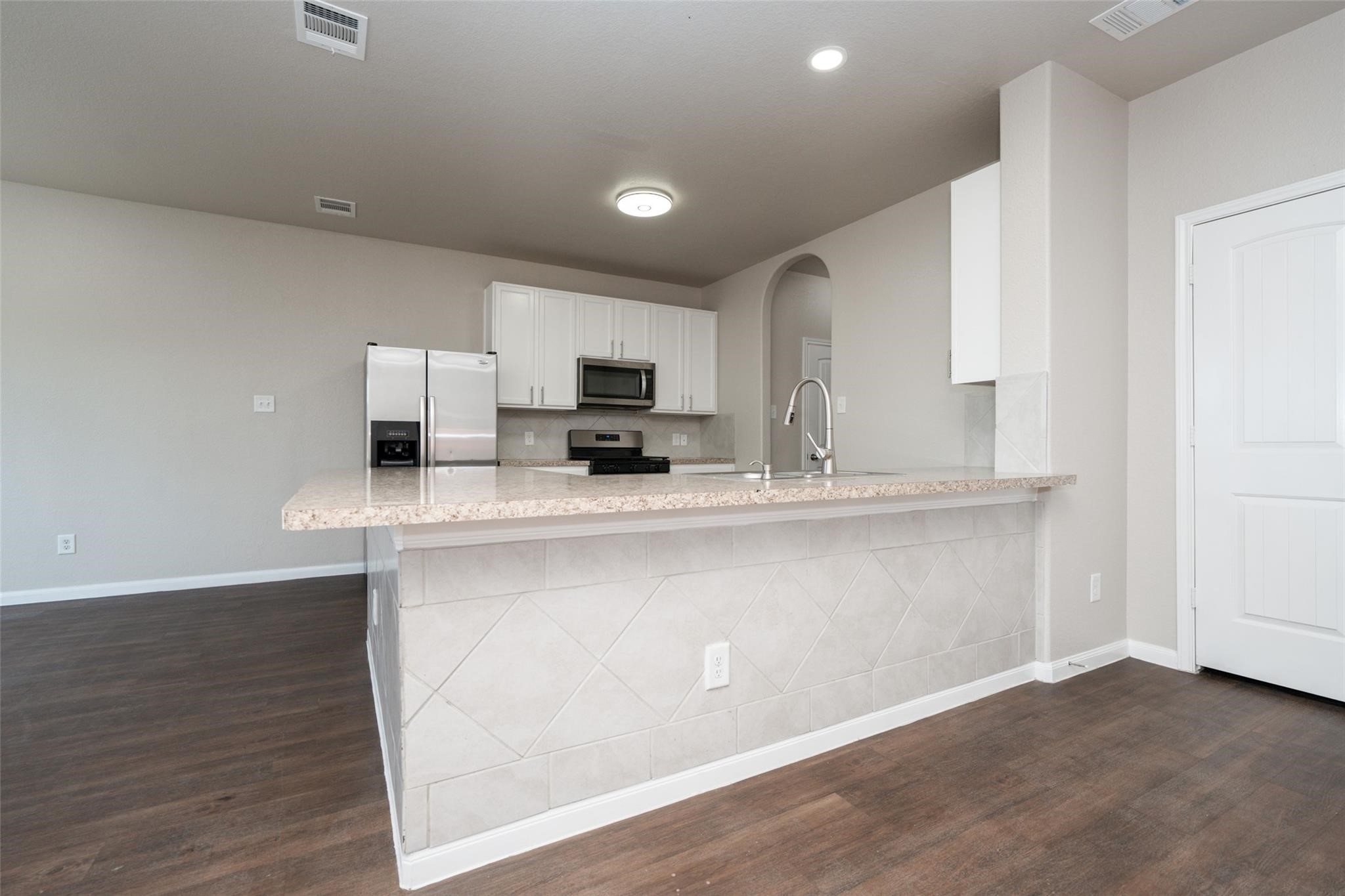 18834 Lansdowne Stream Path Katy, TX 77449 - Photo 3 of 21 a kitchen with stainless steel appliances granite countertop a sink a stove a microwave a sink a refrigerator and white cabinets