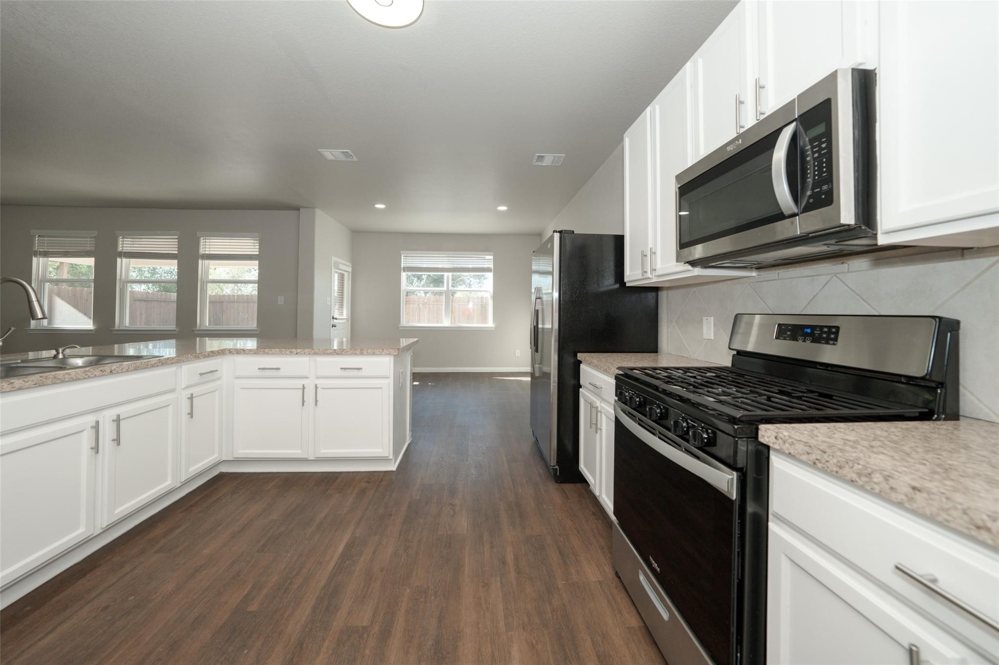 18834 Lansdowne Stream Path Katy, TX 77449 - Photo 6 of 21 a kitchen with stainless steel appliances granite countertop a stove top oven a sink dishwasher and a microwave oven with wooden floor