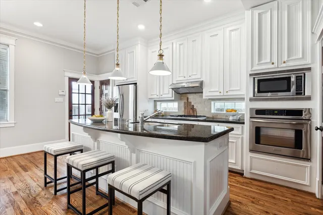 a kitchen with stainless steel appliances granite countertop a stove a sink and a microwave