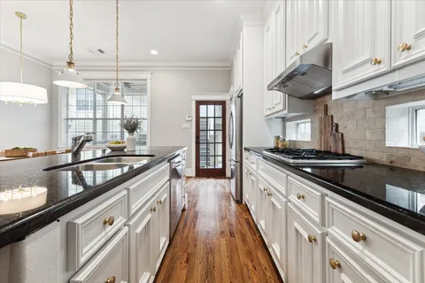 a kitchen with stainless steel appliances granite countertop a sink a stove and a wooden floors