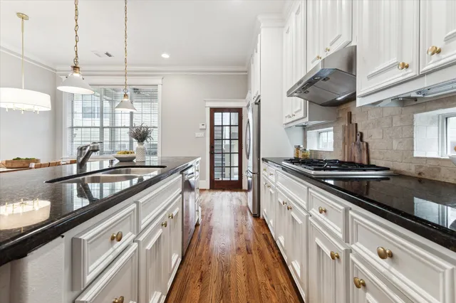 a kitchen with stainless steel appliances granite countertop a sink a stove and a wooden floors