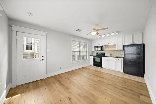 a kitchen with granite countertop a refrigerator oven a sink dishwasher and white cabinets next to a window