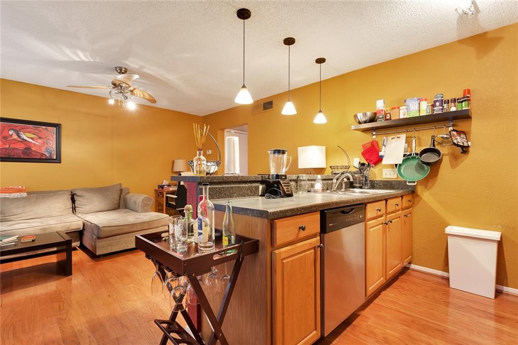 910 Duncan Lane, Unit 35 Austin, TX 78705 - Photo 7 of 20 A warm-toned living space features sleek wood flooring and a kitchen island with pendant lighting.