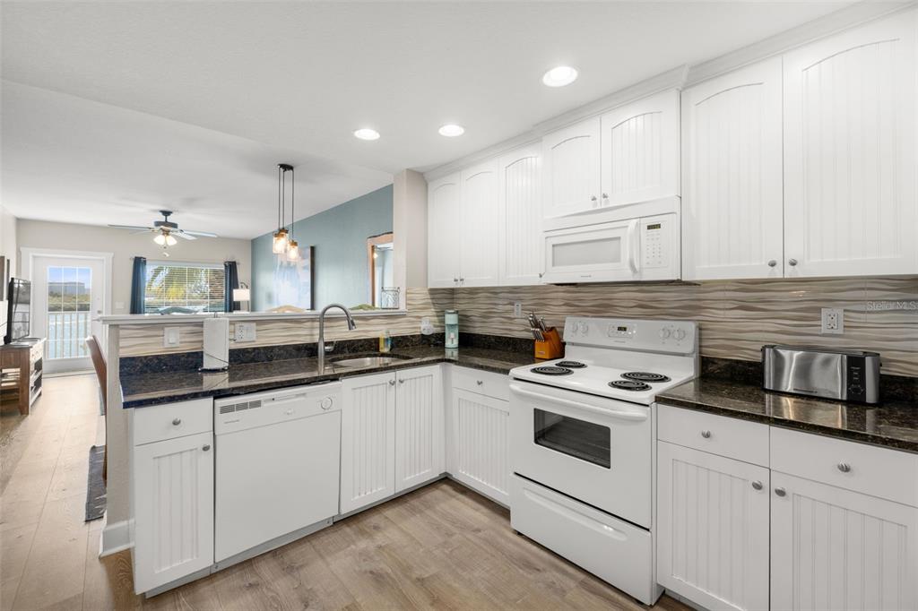 399 2nd Street, Unit 216 Indian Rocks Beach, FL 33785 - Photo 18 of 45 a kitchen with granite countertop white cabinets and white appliances