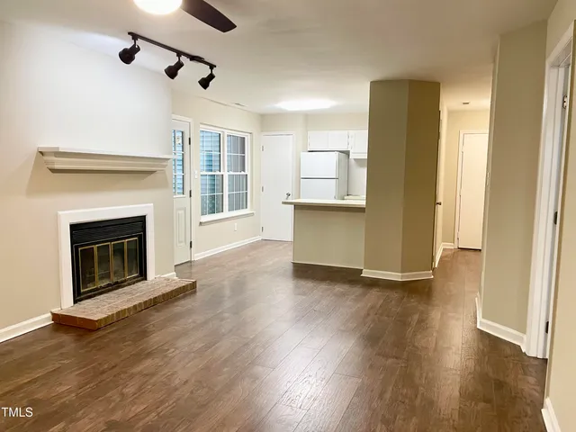 a view of a livingroom with wooden floor a fireplace and windows