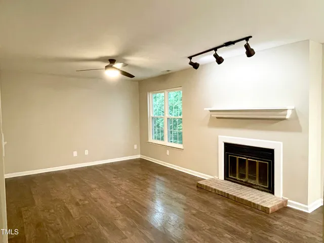 a view of an empty room with a fireplace and a window