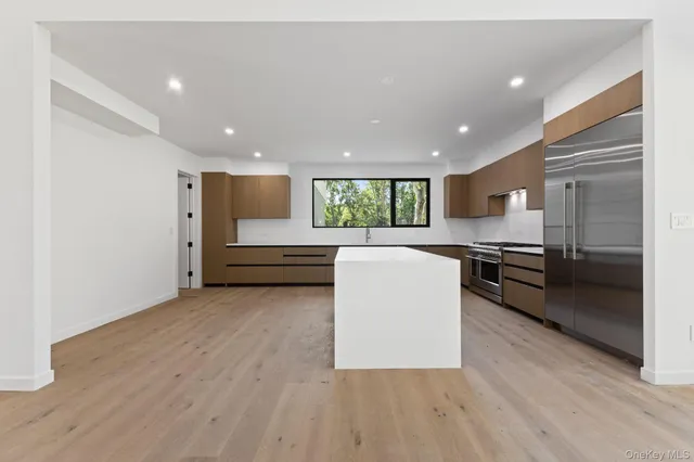 a living room with stainless steel appliances furniture large window and wooden floor