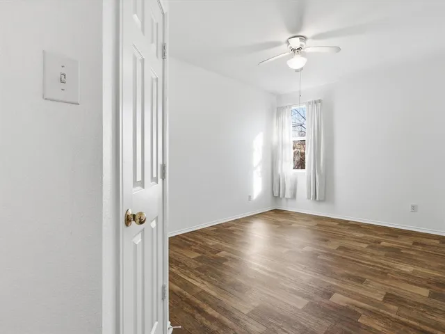 an empty room with wooden floor ceiling fan