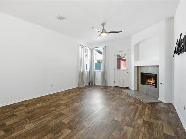 an empty room with windows fireplace and a kitchen view