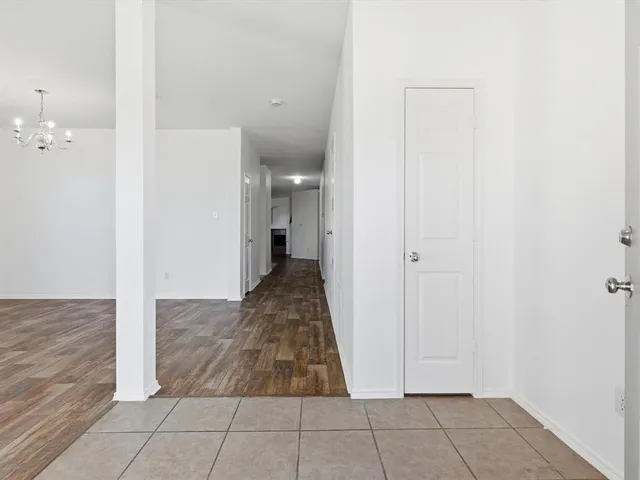 a view of a hallway with wooden floor and a bathroom