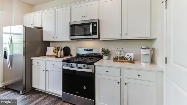 a kitchen with stainless steel appliances granite countertop white cabinets a stove a sink and dishwasher