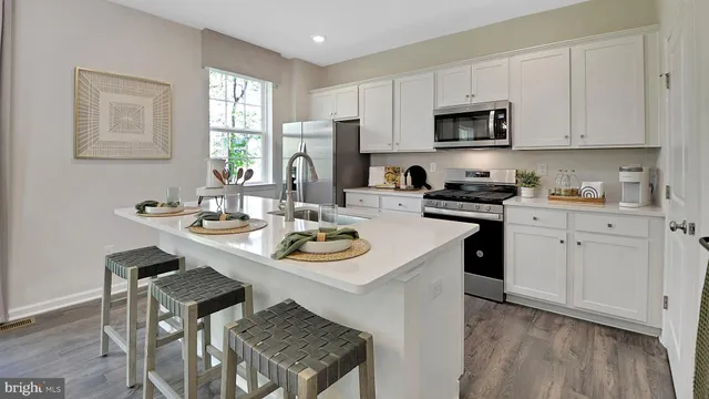 a kitchen with stainless steel appliances kitchen island granite countertop a sink a stove a microwave cabinets and dining table