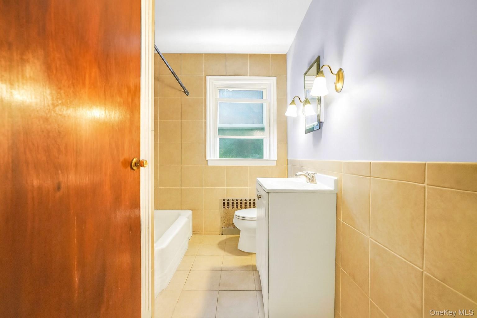 139 Spring Street Ossining, NY 10562 - Photo 14 of 29 Bathroom featuring vanity, shower combination, light tile patterned flooring, tile walls, and radiator heating unit