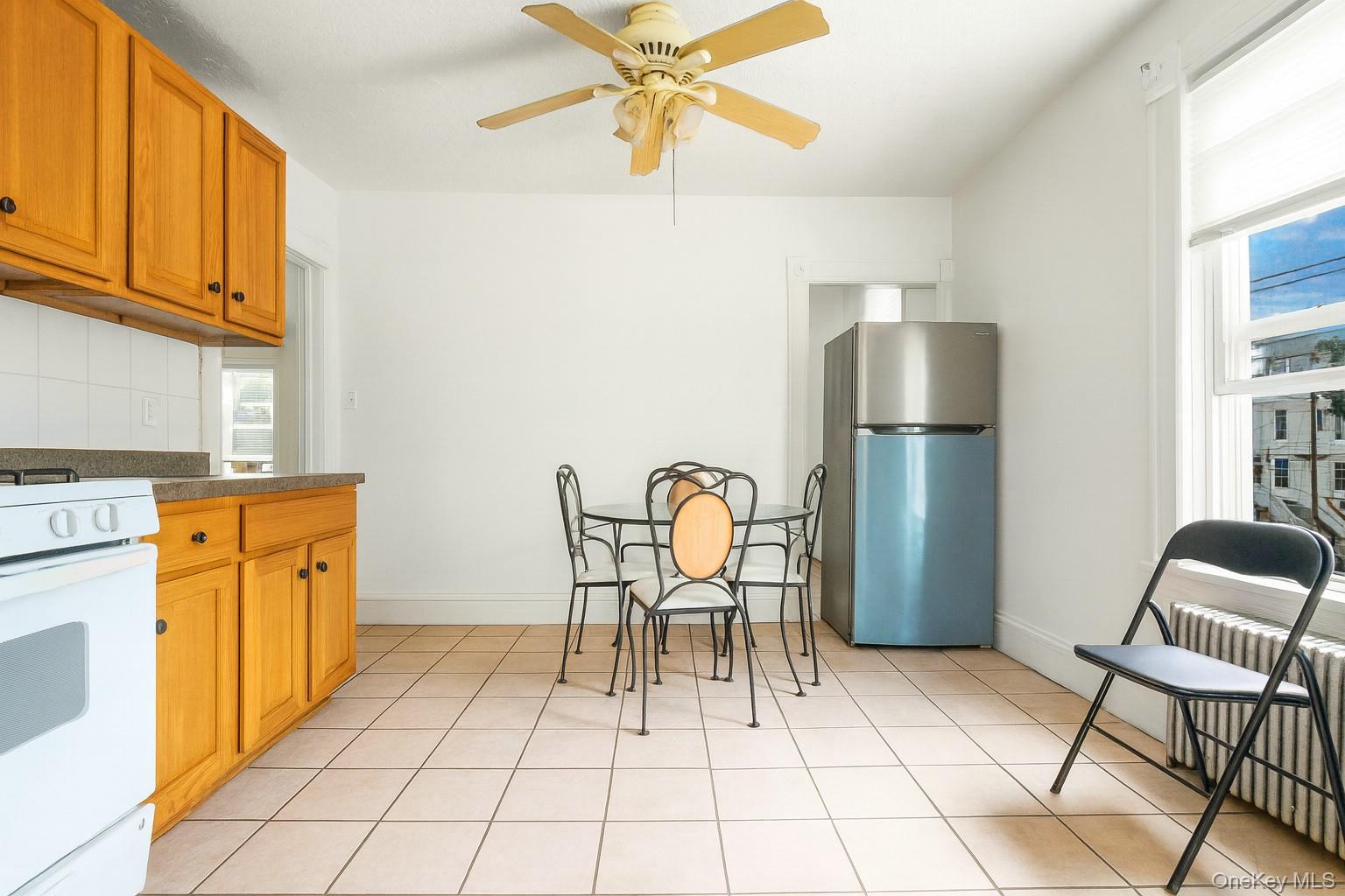 139 Spring Street Ossining, NY 10562 - Photo 6 of 29 Kitchen with dark countertops, freestanding refrigerator, white range with gas stovetop, ceiling fan, and radiator heating unit
