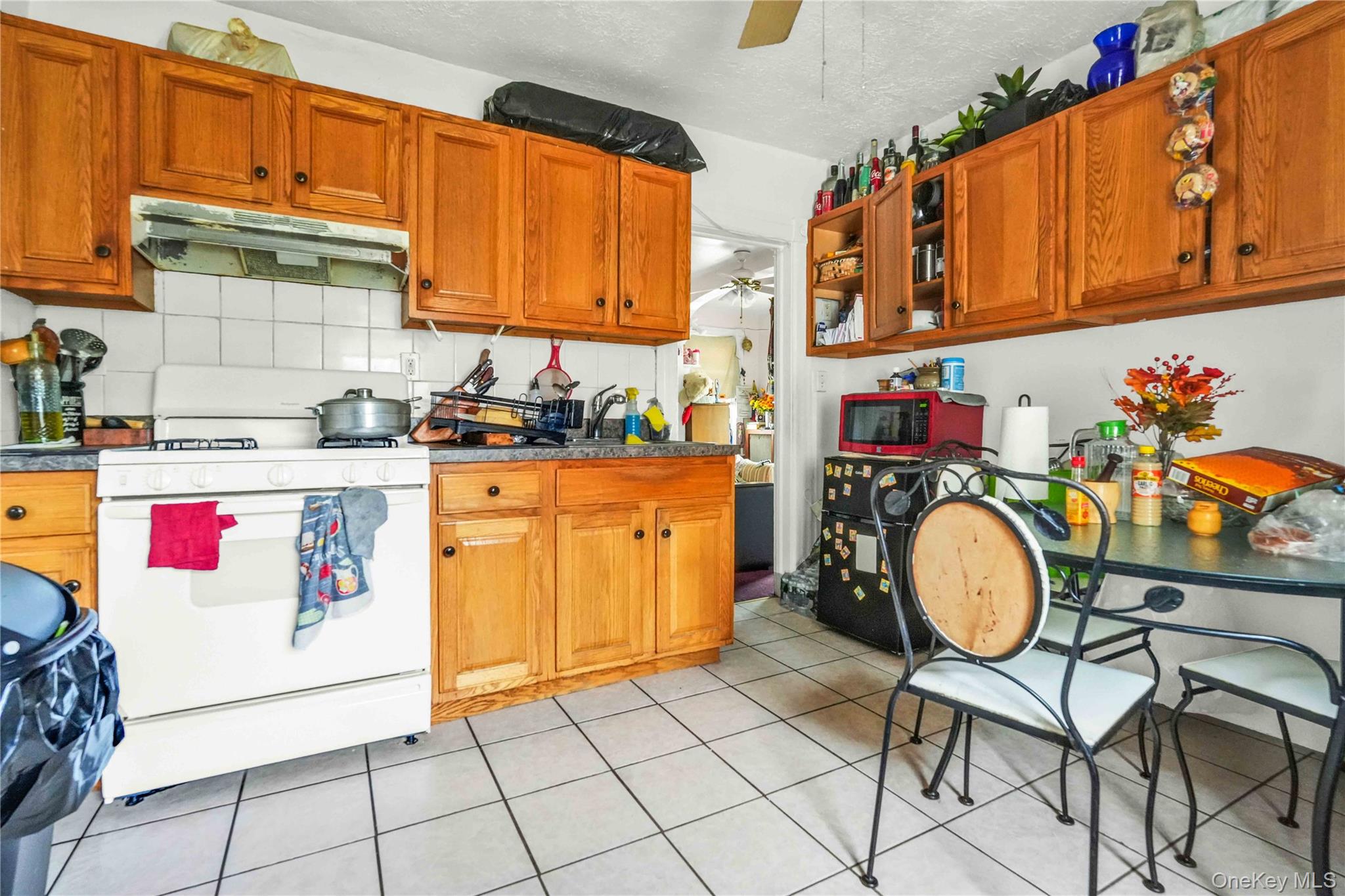139 Spring Street Ossining, NY 10562 - Photo 7 of 29 Kitchen featuring gas range gas stove, ceiling fan, backsplash, under cabinet range hood, and a textured ceiling