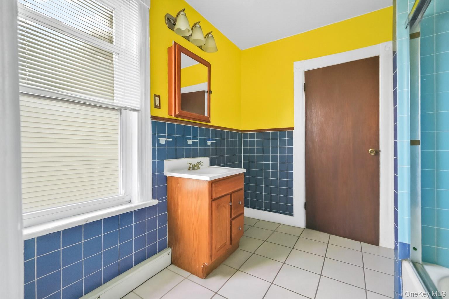 139 Spring Street Ossining, NY 10562 - Photo 9 of 29 Bathroom with tile walls, wainscoting, light tile patterned floors, vanity, and baseboard heating