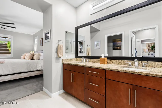 a en suite bathroom with a granite countertop double vanity sink and a large mirror