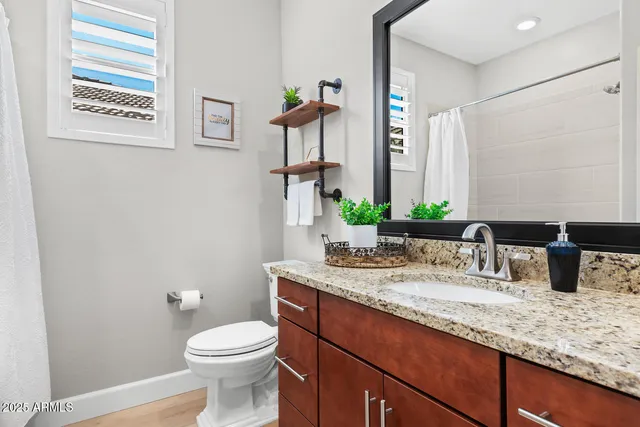 a bathroom with a granite countertop toilet sink and mirror