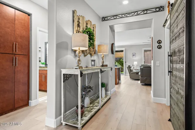 a hall way with furniture a mirror and a wooden floor