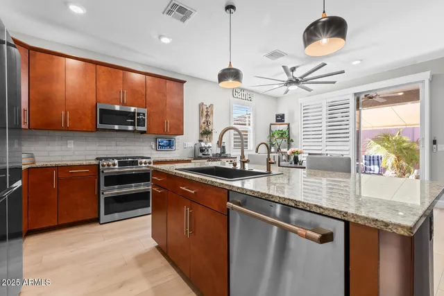 a kitchen with stainless steel appliances granite countertop a sink a stove and a refrigerator