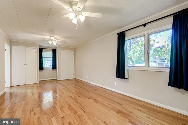 an empty room with wooden floor and windows