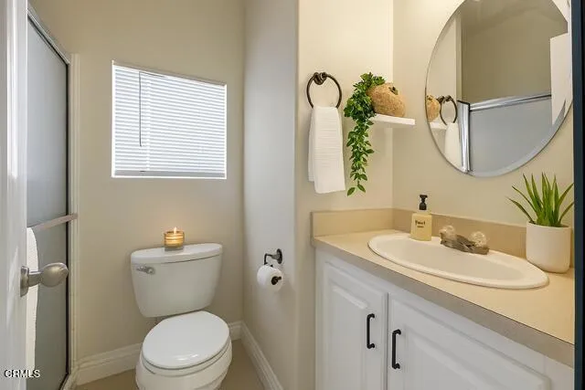 a bathroom with a toilet a sink a mirror and a window