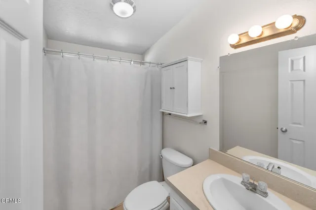 a bathroom with a sink a toilet and shower curtain