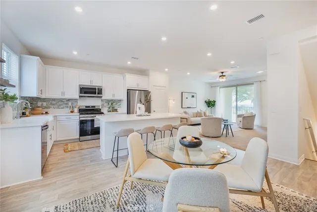 a kitchen with stainless steel appliances granite countertop a table chairs and a refrigerator