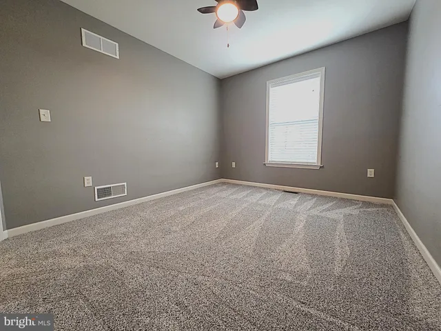 an empty room with a window and a ceiling fan
