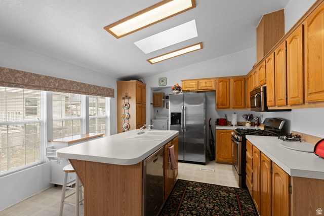 2600 North Hill Field Road, Unit 134 Layton, UT 84041 - Photo 14 of 41 Kitchen featuring lofted ceiling, light flooring, stainless steel appliances, a skylight, and an island with sink