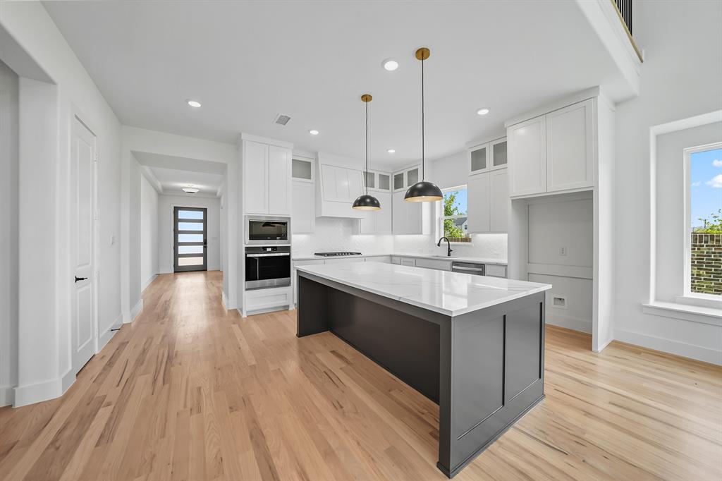 587 Mayfair Lane Frisco, TX 75033 - Photo 16 of 36 Kitchen with glass insert cabinets, white cabinetry, stainless steel appliances, pendant lighting, and light stone countertops