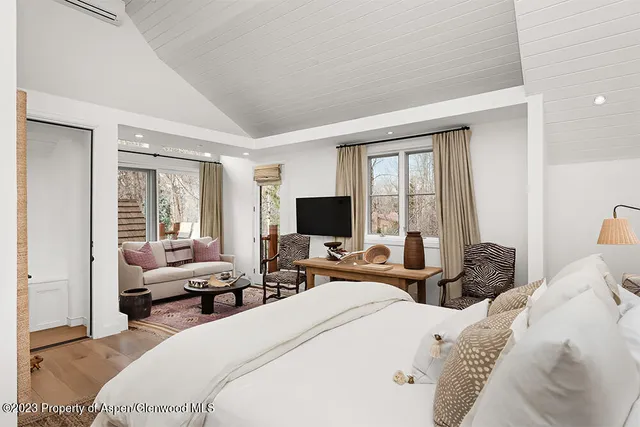 a bedroom with a bed and large windows