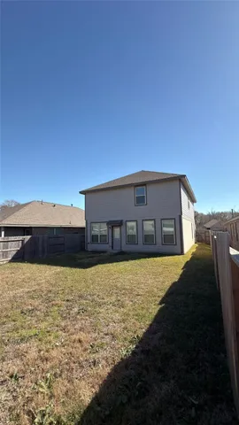 a backyard of a house with large trees and wooden fence