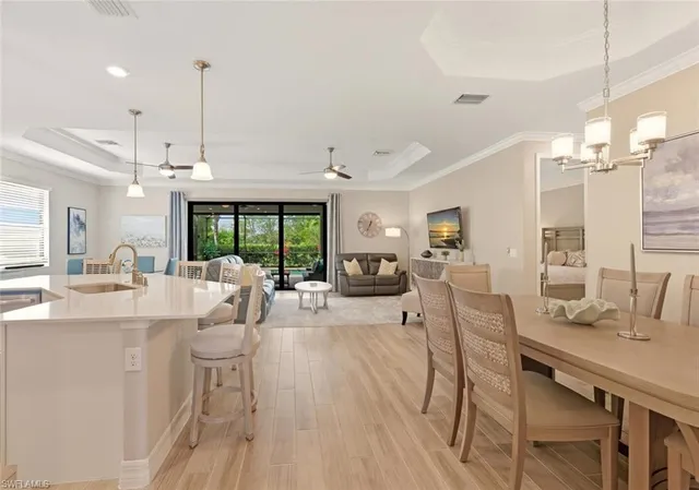 a view of a dining room and livingroom with furniture wooden floor a rug a flat screen tv a rug and a chandelier